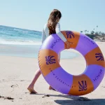 Meisje in het zwembad met een Swim Essentials zwemband tijdens een zonnig zwemmoment.