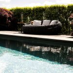 Luxe zwembad in zomerse tuin met helder blauw water en zonnige sfeer.